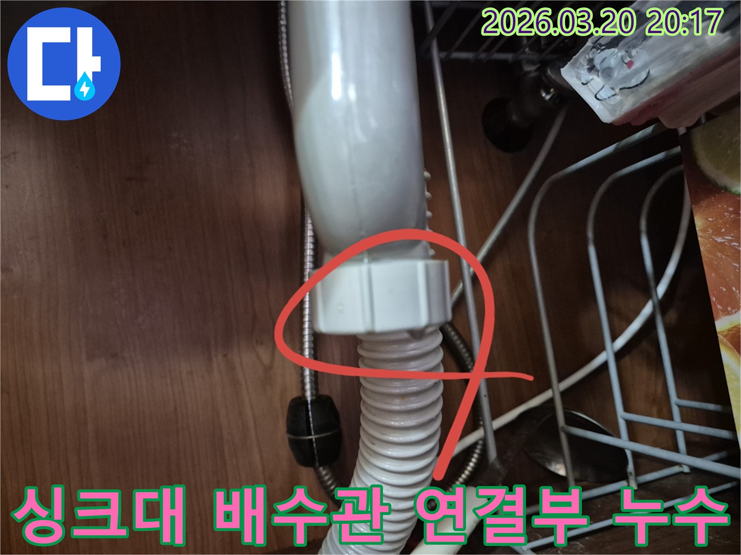 싱크대 하부장 내부에서 발견된 배수관 연결 부위의 물샘 현장을 보여주는 사진입니다