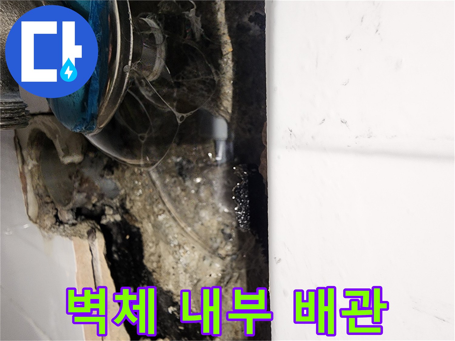 타일 제거 후 드러난 젖은 벽면과 금속 배관 부속
