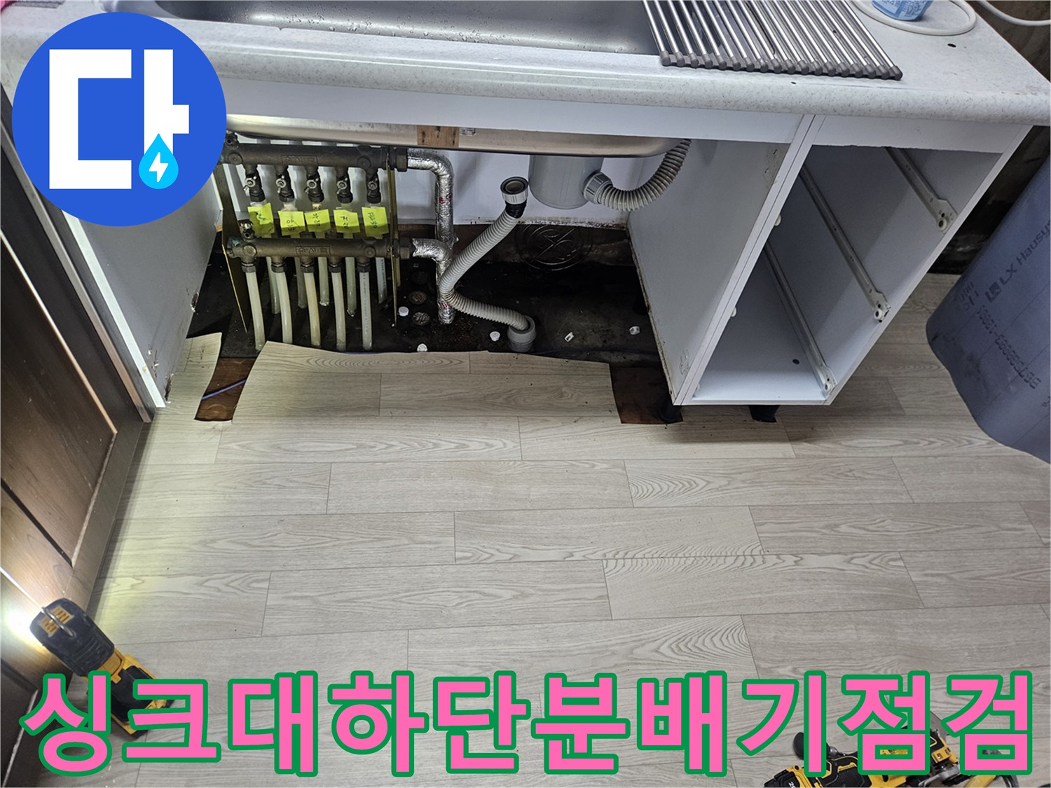 싱크대 하부 공간에 노출된 난방 분배기와 젖은 배관 주변