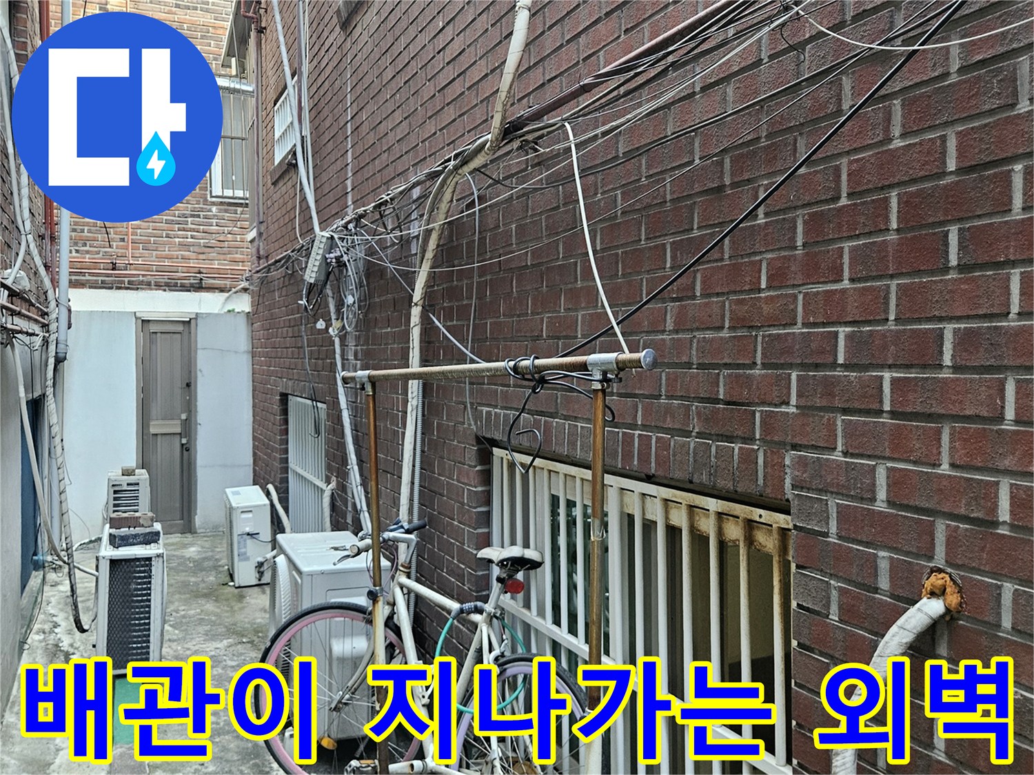 건물 벽면을 따라 설치된 배관과 실외기 및 자전거가 있는 현장