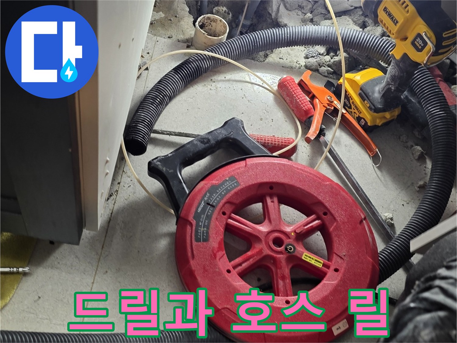 싱크대 하단 작업 부위 옆에 놓인 드릴과 호스 장비