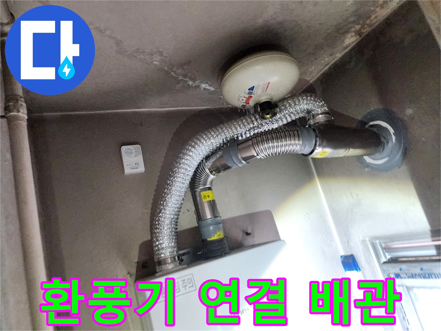 천장 환풍기와 연결된 은색 주름진 배관의 모습입니다.