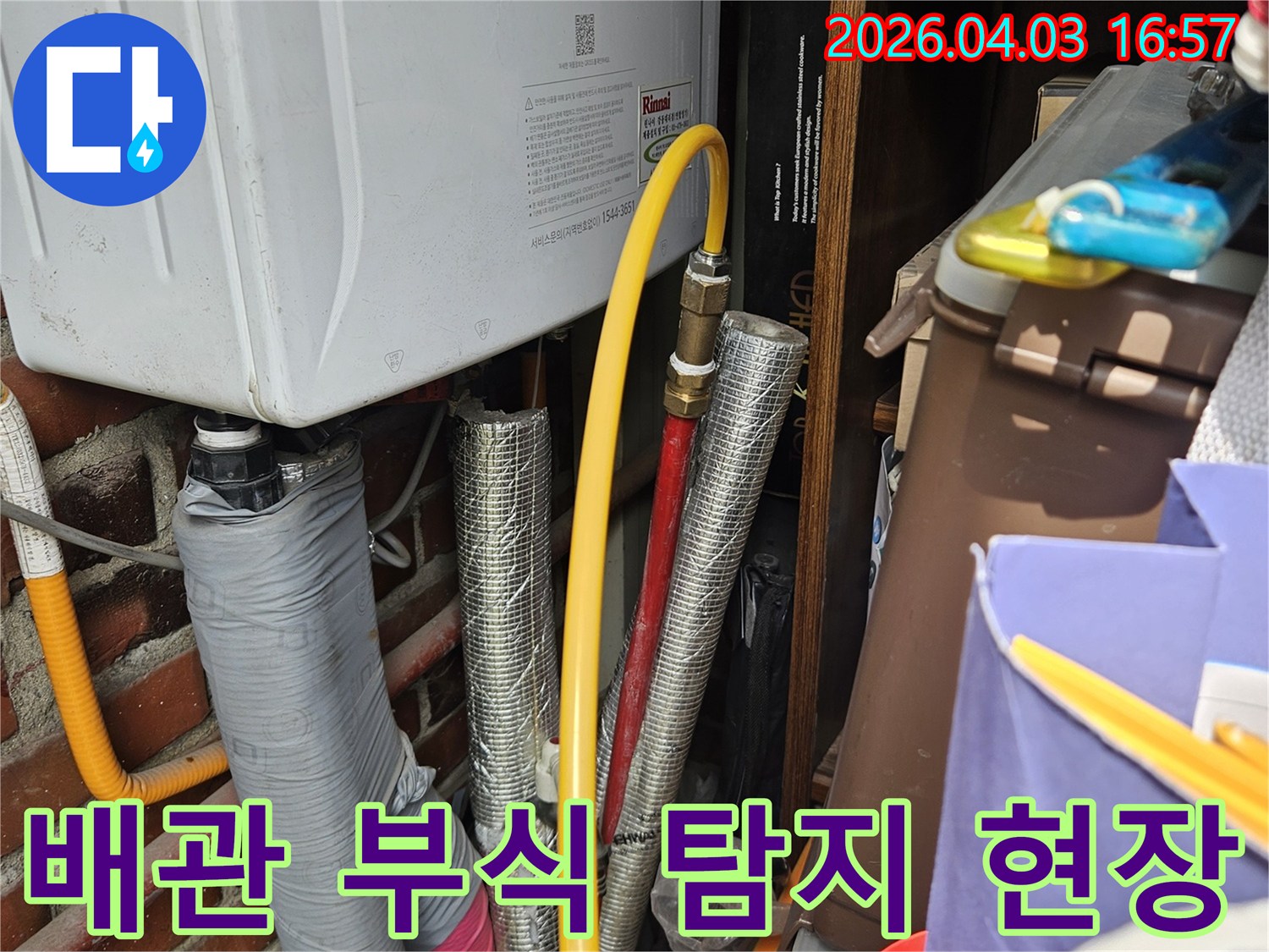 오래된 주택의 보일러실에서 발견된 다양한 배관들의 모습입니다-특히 가스관과 온수관의 접합부를 중점적으로 살펴보고 있습니다.