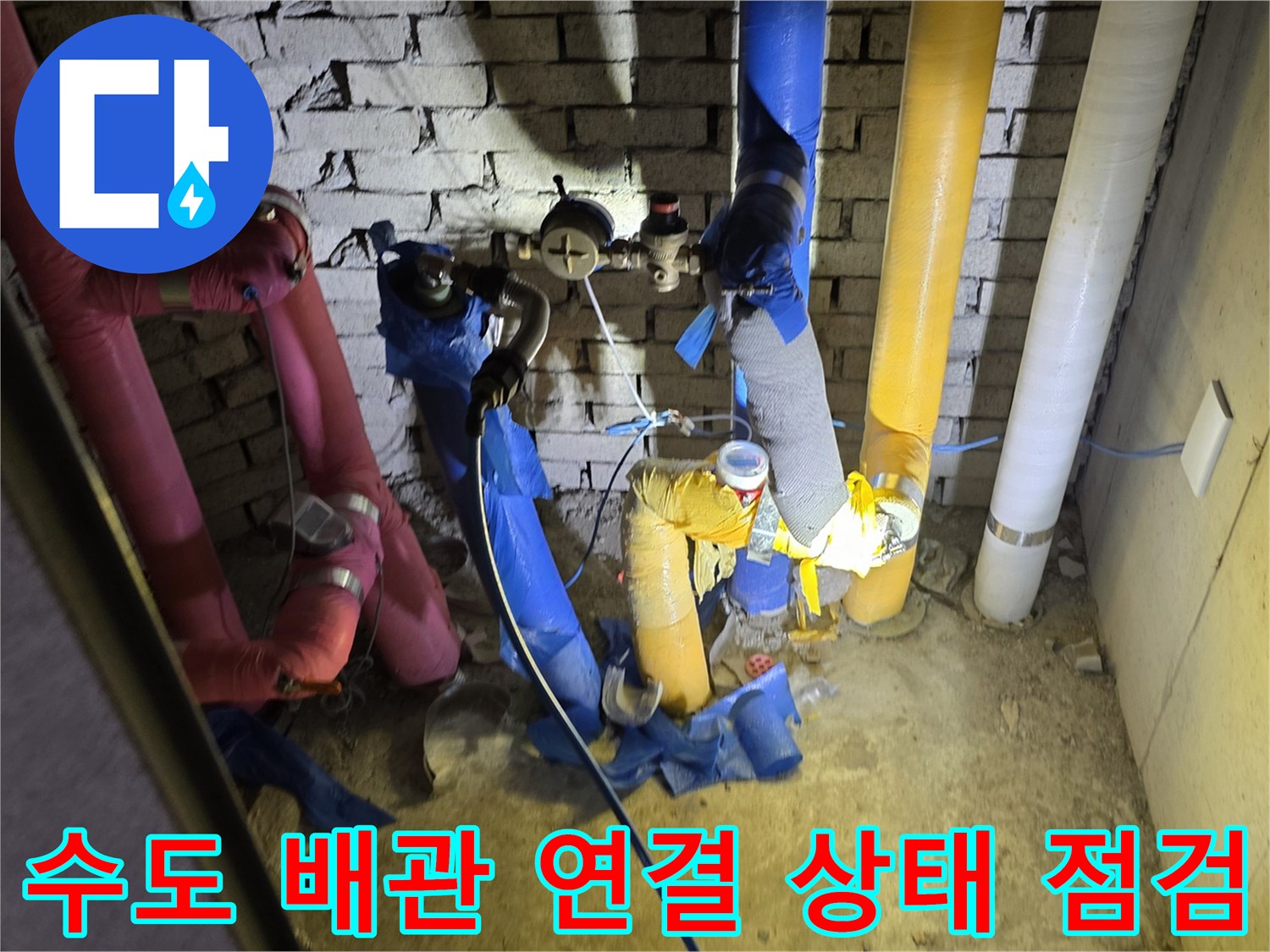 분홍색과 파란색 수도 배관의 접합 부위를 면밀히 관찰하는 작업 모습