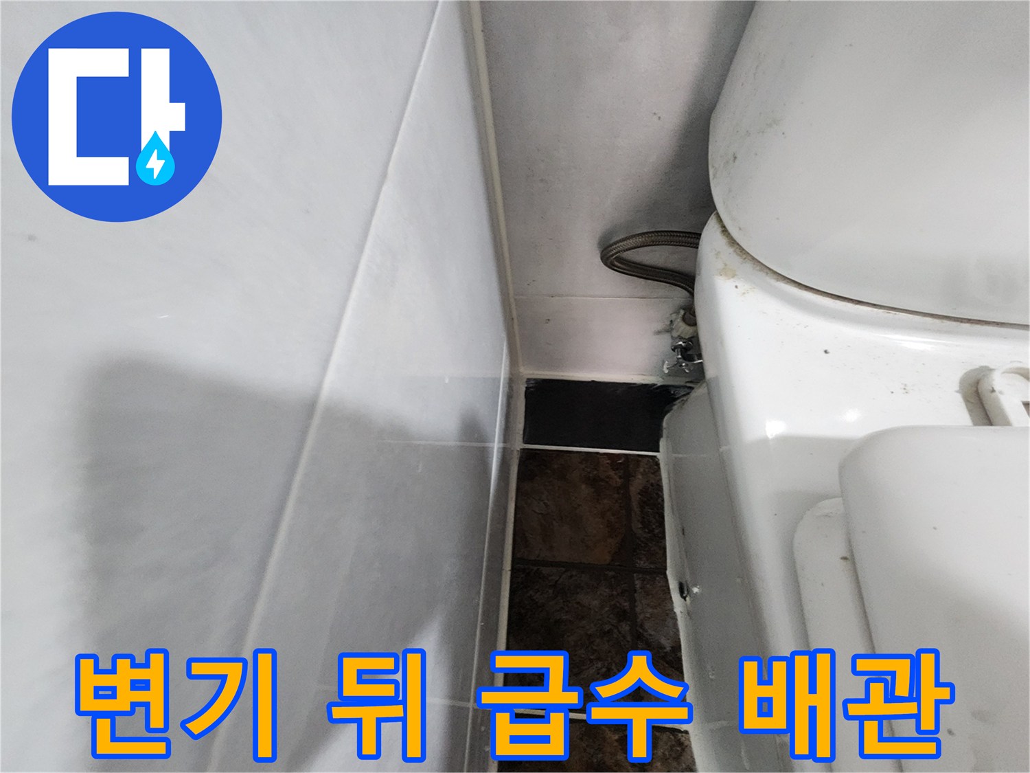 변기 뒷면의 배관 연결부와 타일 벽면 모습