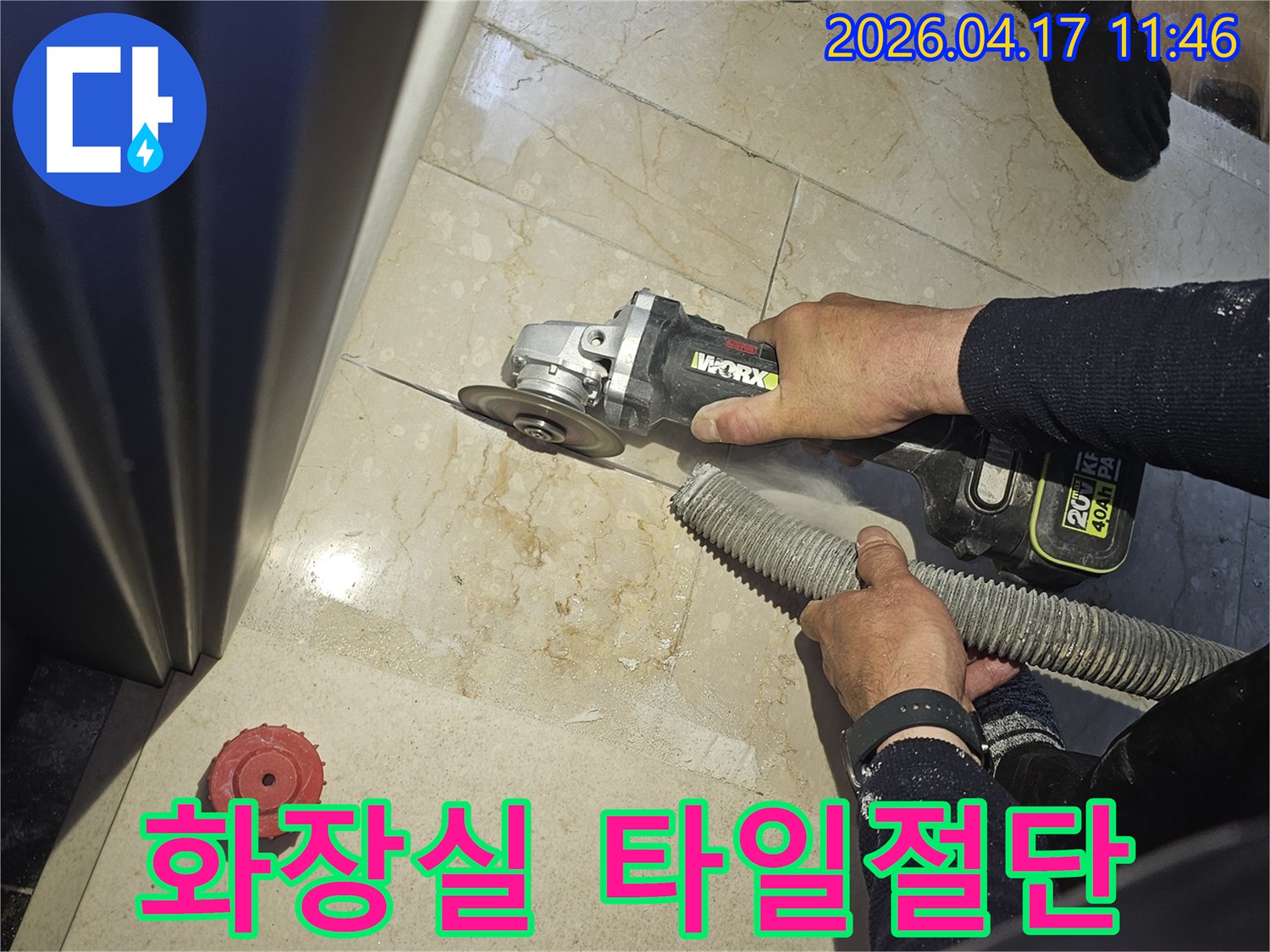 화장실 누수 보수를 위해 작업자가 그라인더로 바닥 타일을 절단하고-있으며-동시에-흡진기로-먼지를-제거하여-깨끗한-작업-환경을-유지하는-모습입니다.