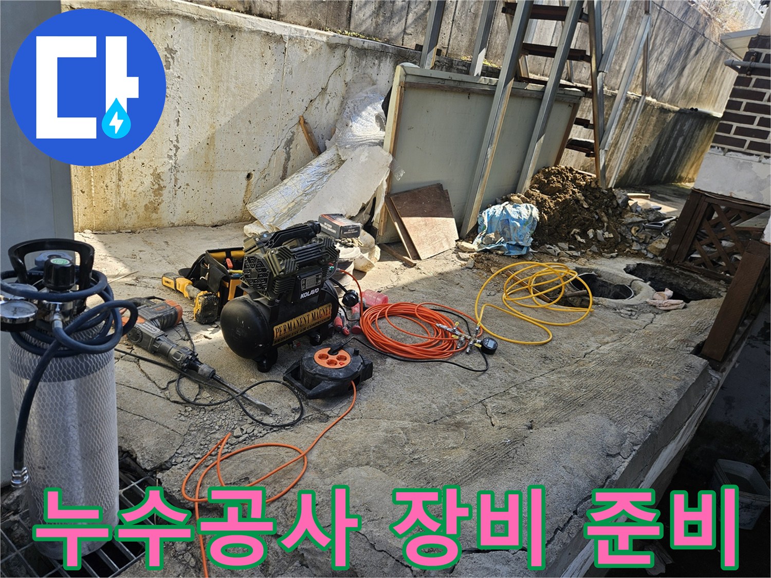 누수 공사 현장에서-에어 콤프레셔-함마드릴-호스-전선릴 등-다양한 전문 장비들이-콘크리트 바닥 위에-정돈된 채-작업 시작 전-점검을 기다리는 모습