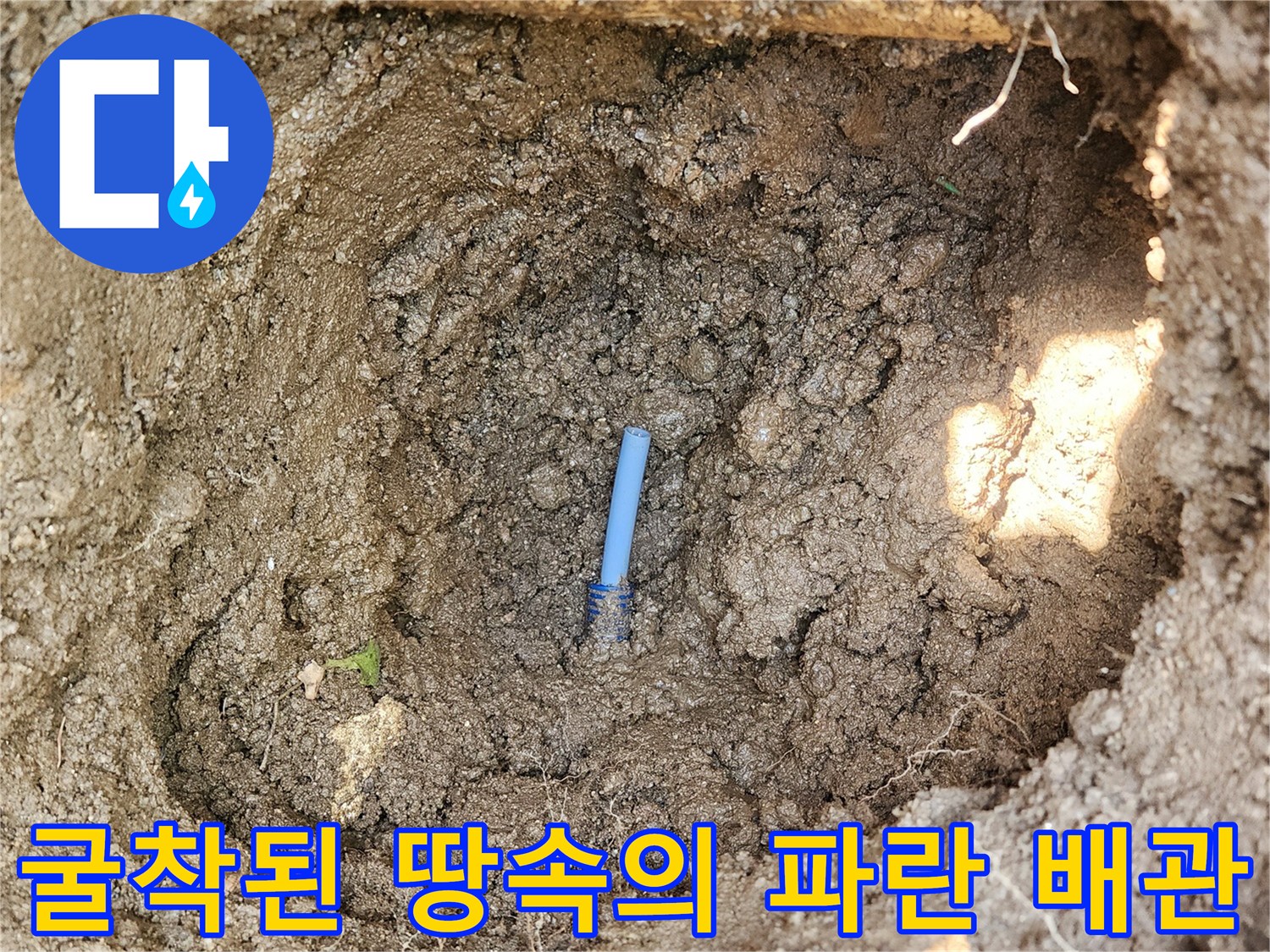 흙 속에 드러난 파란색 관과 파손된 연결 커넥터 부위