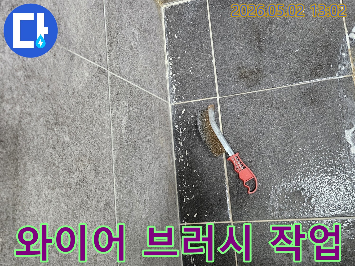 누수로 인해 생긴 곰팡이를-효과적으로 제거하기 위해-타일 바닥에 놓인 와이어 브러시