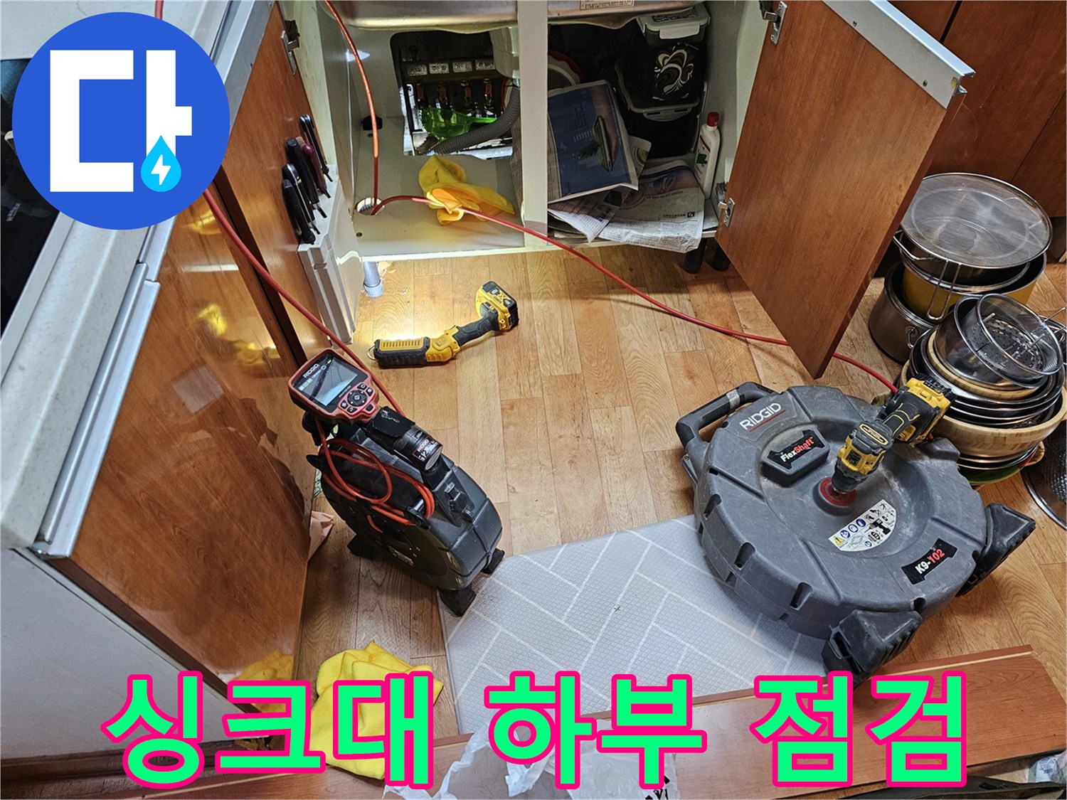 싱크대 하부장 아래에 놓인 내시경 카메라와 작업용 전동 드릴
