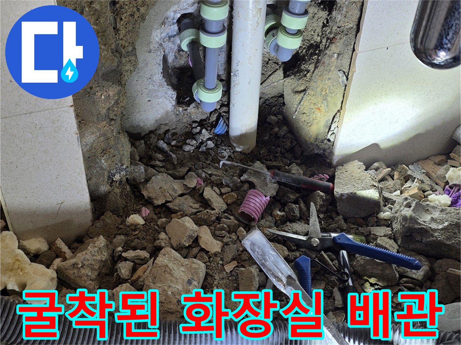 타일 제거 후 드러난 젖은 배관과 주변 공사 자재들