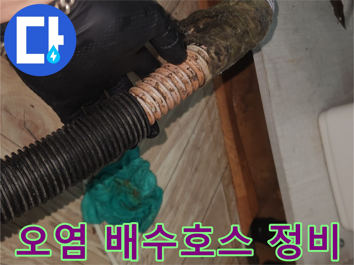 전문 엔지니어가-검은색 작업 장갑을 착용하고-오랜 사용으로 오염된 싱크대 배수 호스를-꼼꼼하게 점검하는 현장 사진