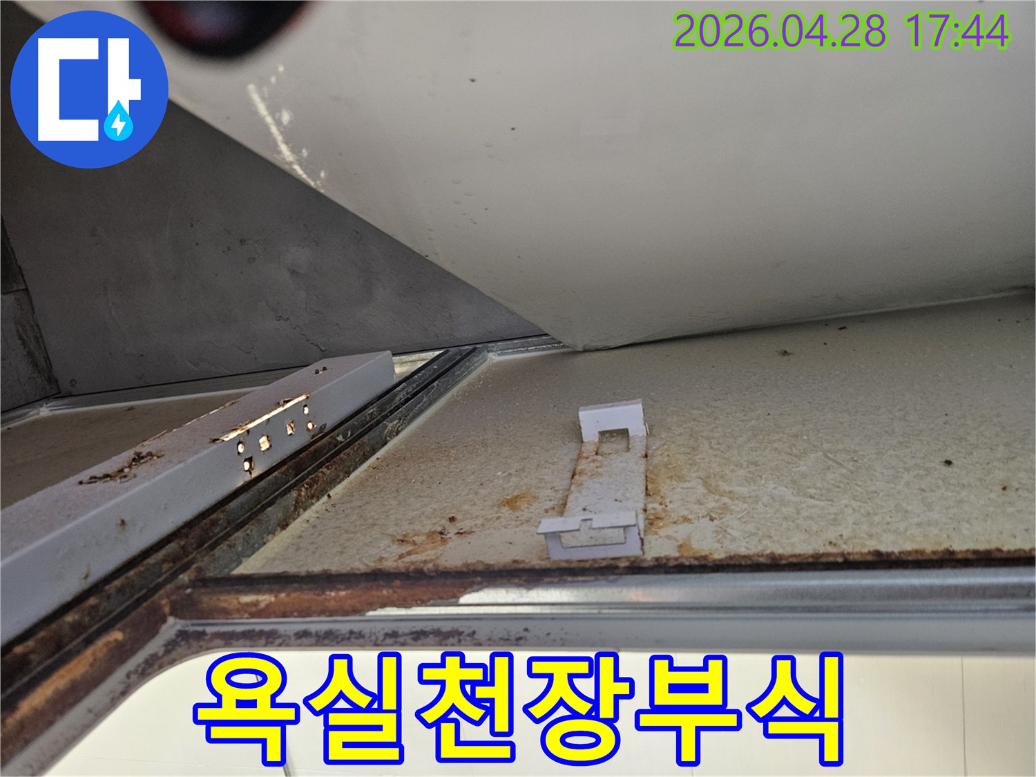 아래층 욕실 천장에서 발견된 심각한 누수 흔적을 보여주는 사진입니다-녹슨 금속 구조물과 변색된 천장 마감재가 명확하게 보입니다.