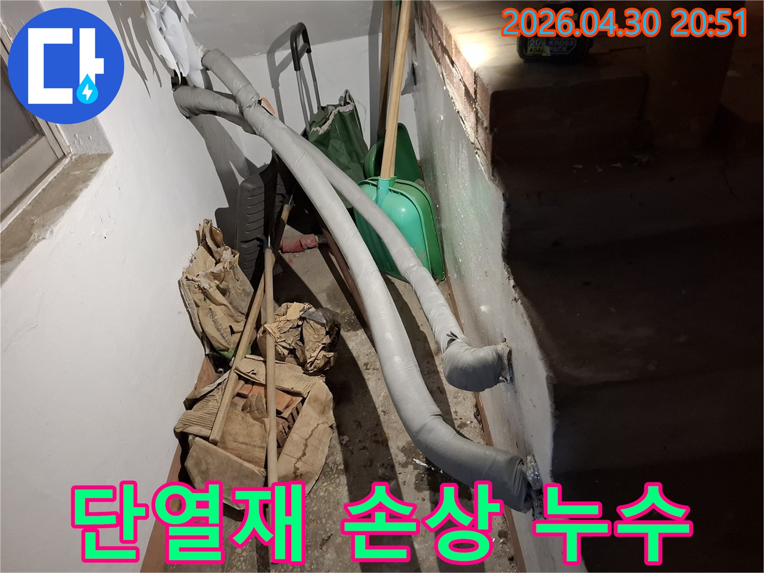 이 이미지는 지하 공간에 설치된 단열 처리된 배관과-주변에 놓인 공사 자재들을 보여줍니다.