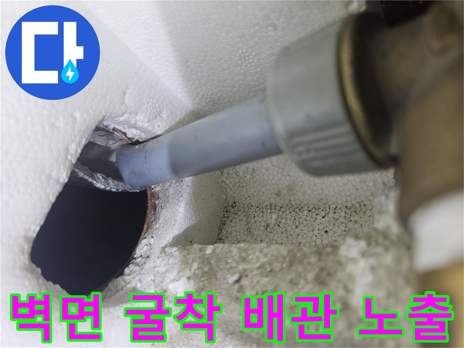 벽면을 절개하여 드러난 수도 배관의 연결 부위와 주변 마감재 모습
