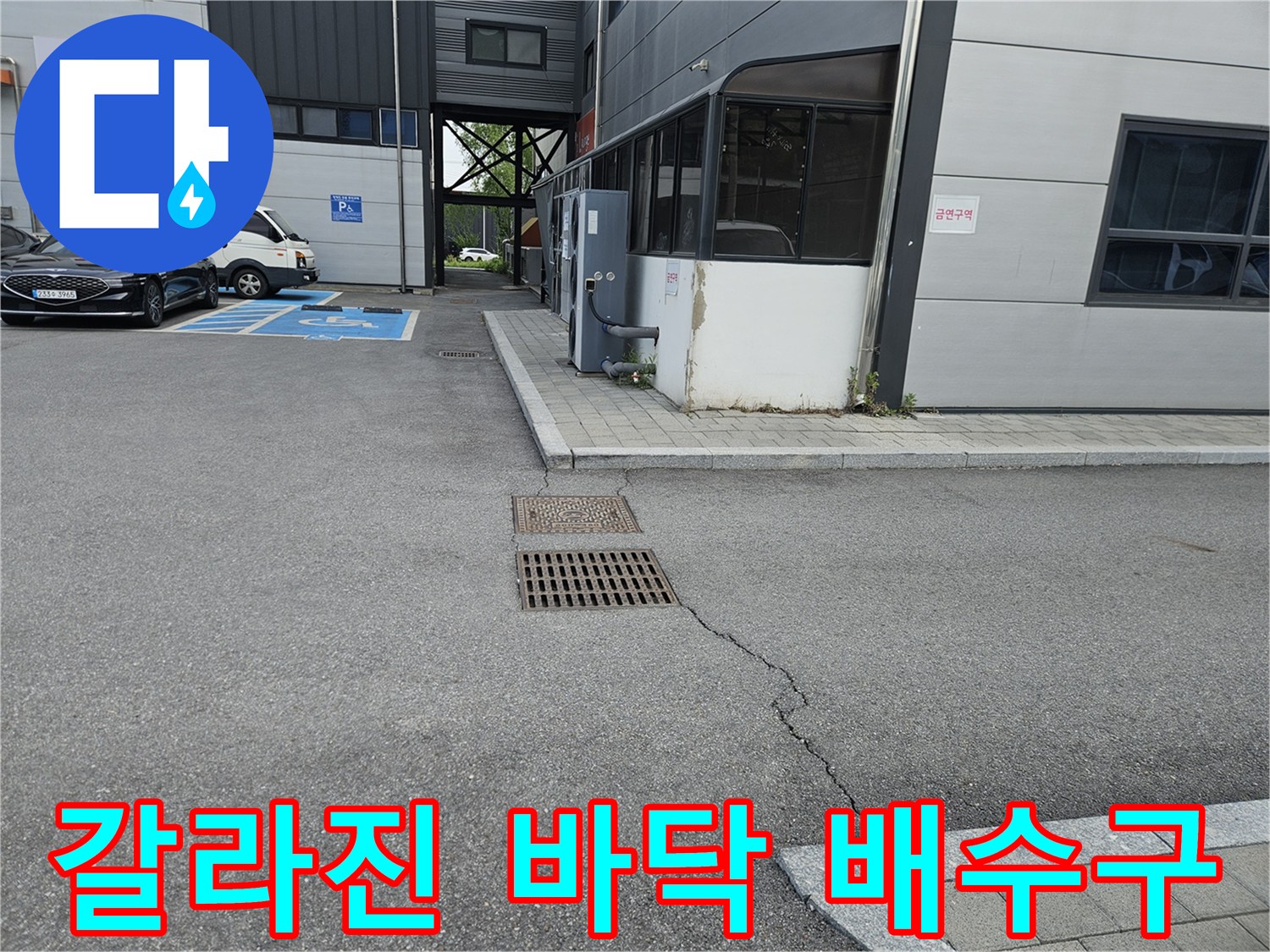 건물 주차장 부근-균열된 아스팔트와 철제 배수구