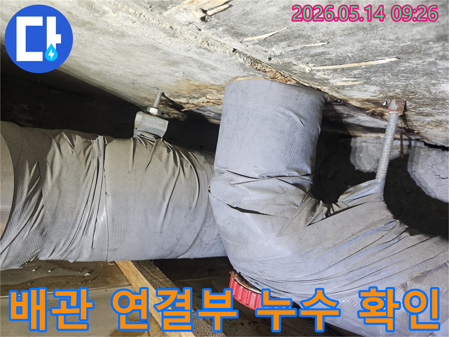 천장 배관의 연결 부위에서 물이 새어-단열재가 젖고 주변에 물방울이 맺힌-누수 현장을 보여줍니다