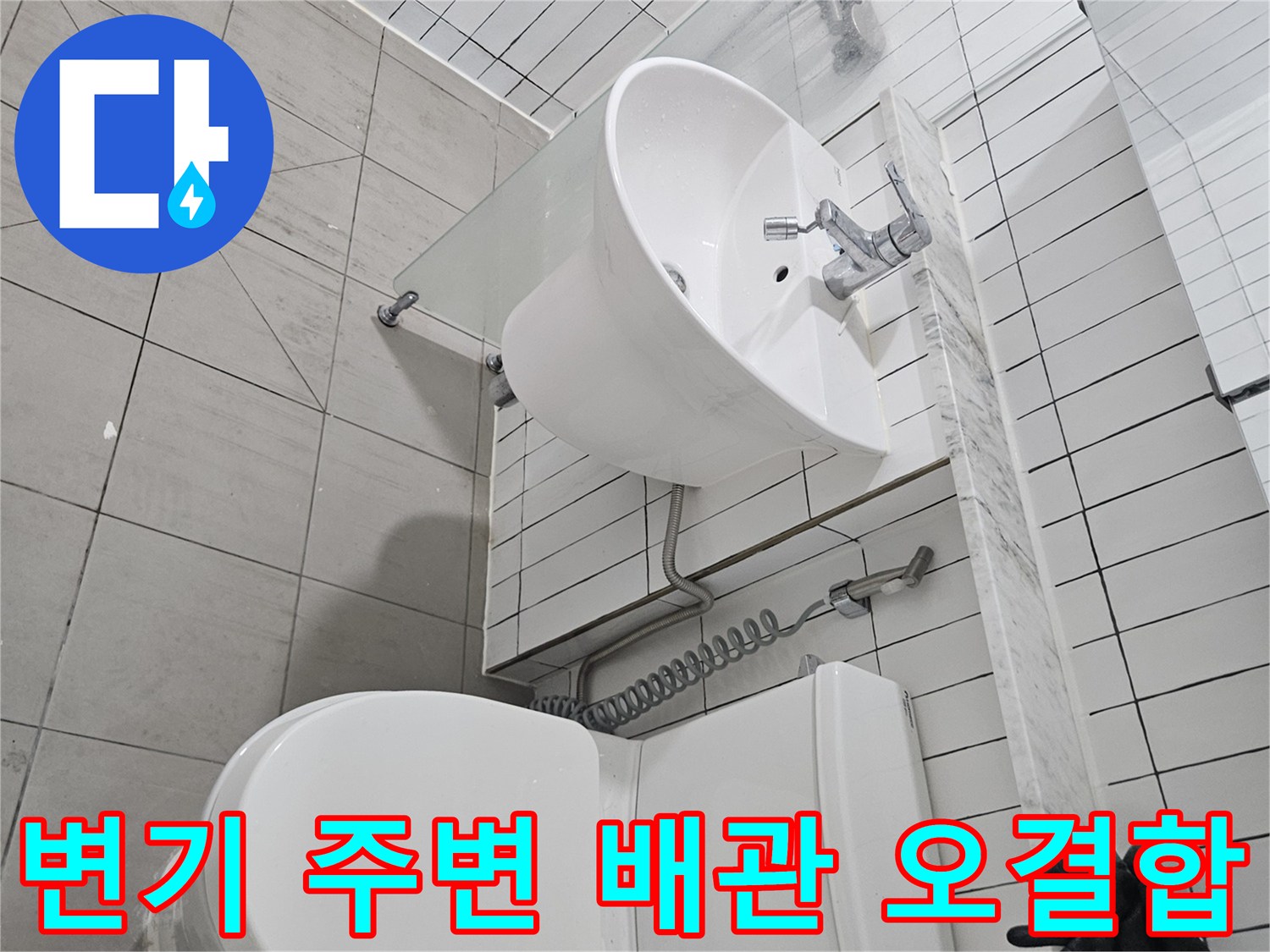 벽면 타일과 연결된 변기 및 세면대 하부의 복잡한 배관 모습