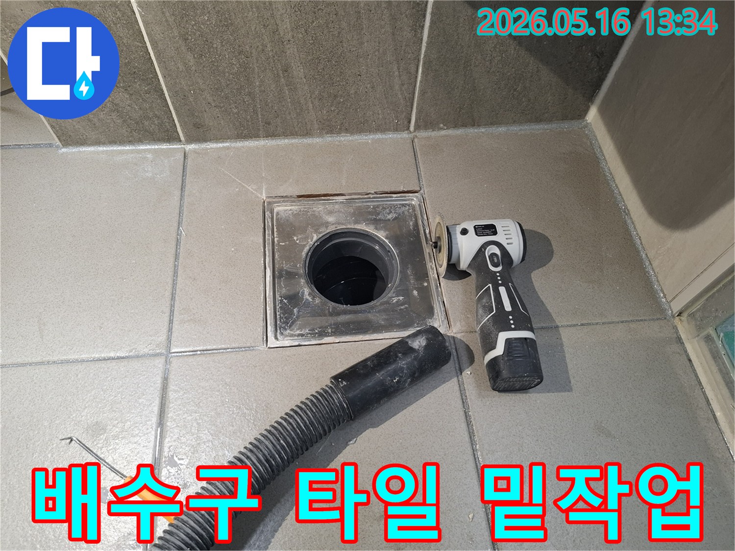 누수 엔지니어가 욕실 배수구 주변의 타일 교체 전-밑작업을 위해-전동 공구로 기존 마감재를 제거하고-흡입 호스로 현장을 정리하는 중입니다