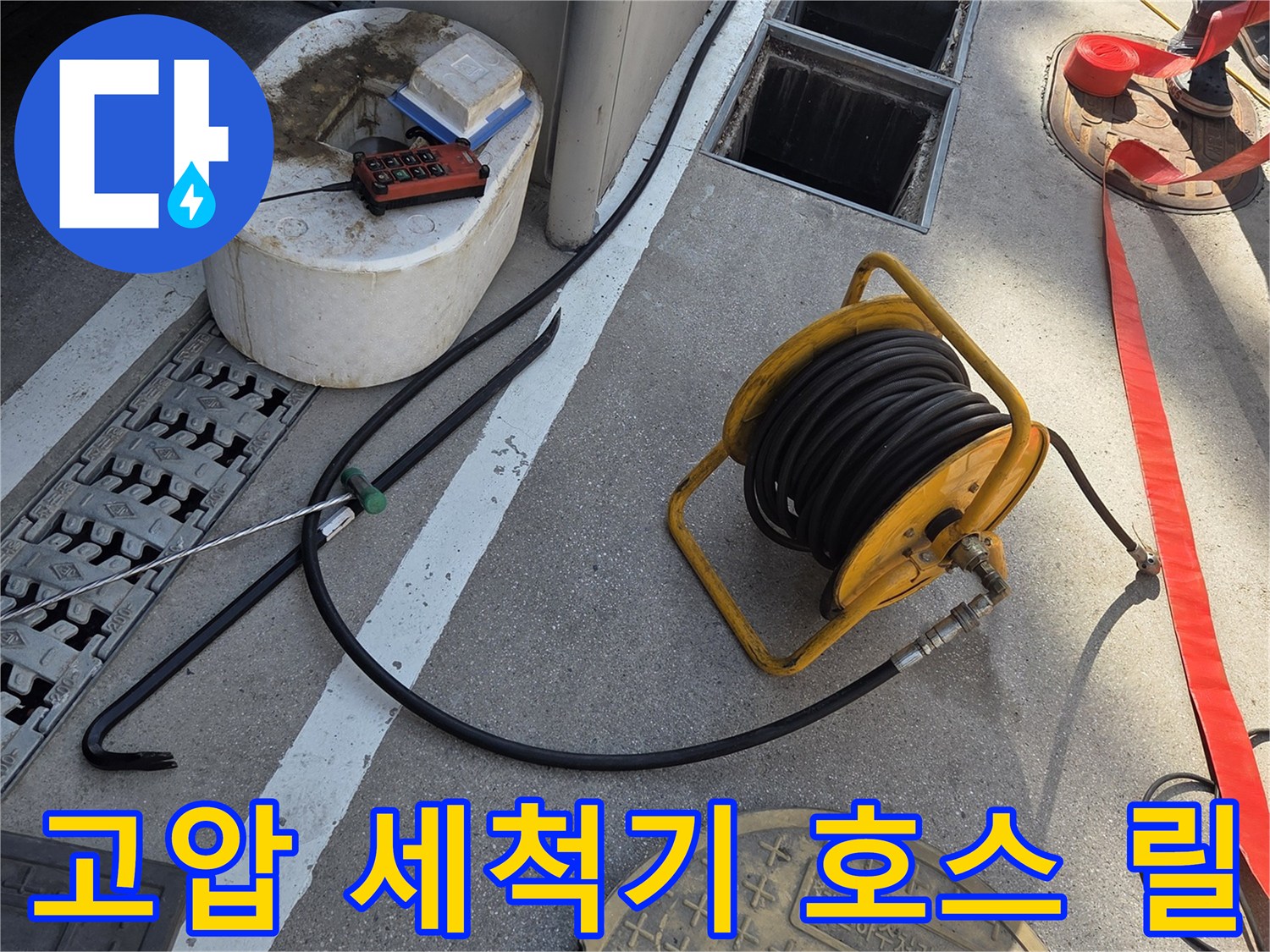 맨홀 뚜껑 옆에 놓인 노란색 배관 세척용 장비