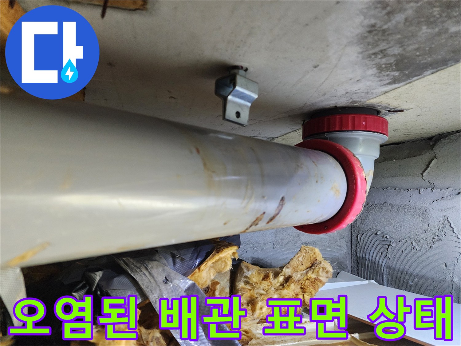 누수로 오염된 오수관-배관 주변의 물자국과 젖은 마감재를 보여줍니다.