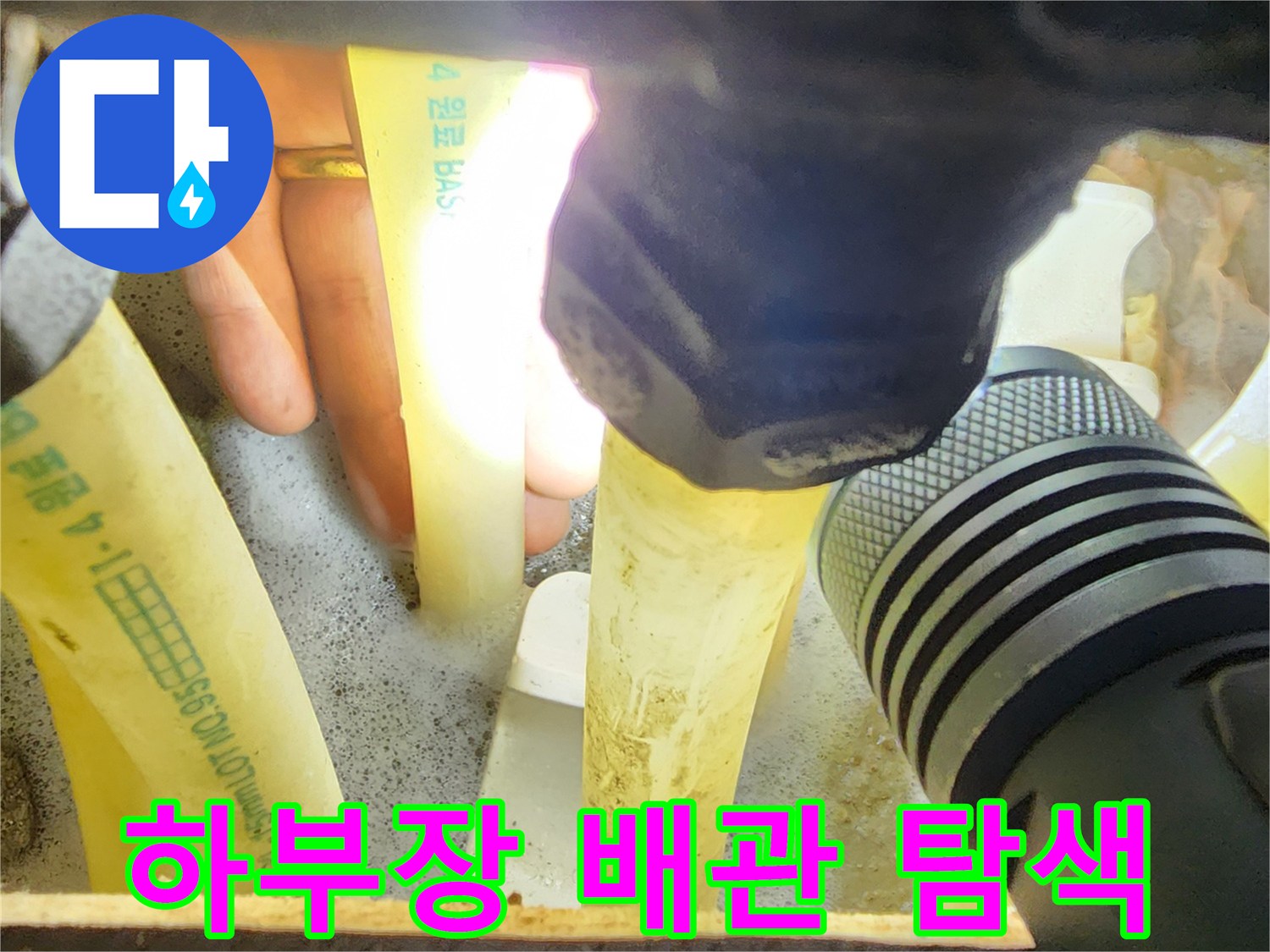 손전등 빛으로 비춘 싱크대 아래쪽 하얀색 분배기 배관