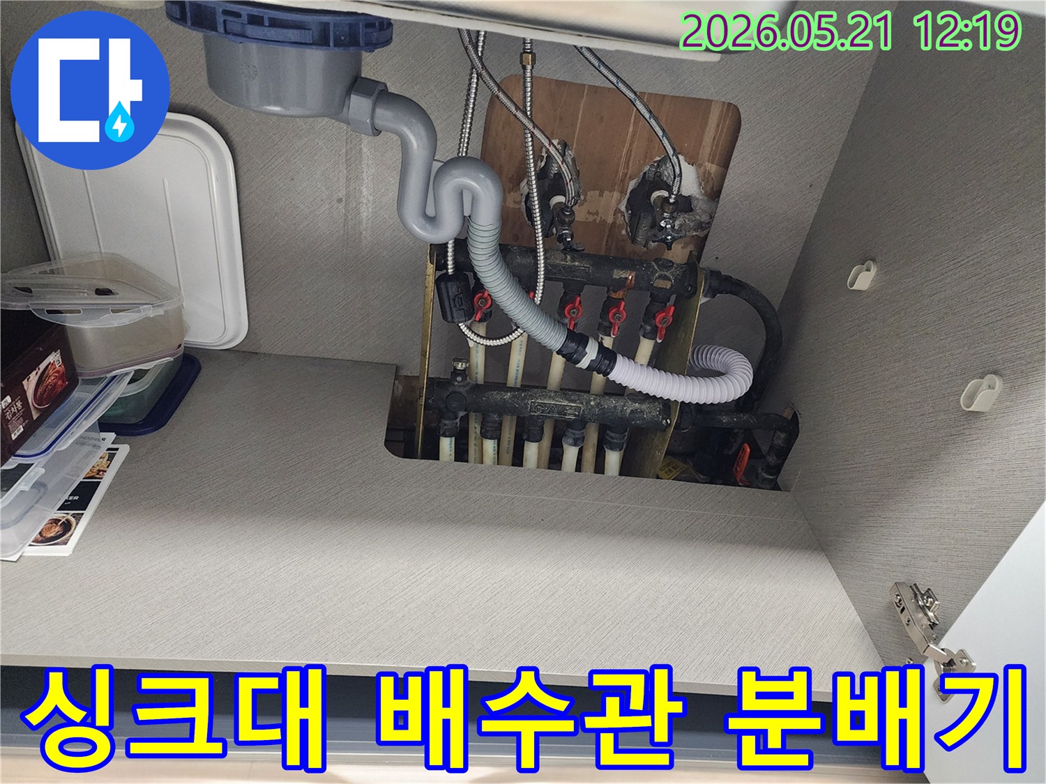 싱크대 아래 복잡하게 얽힌 배수관과 분배기-누수 위치를 찾기 위한 현장 사진입니다.
