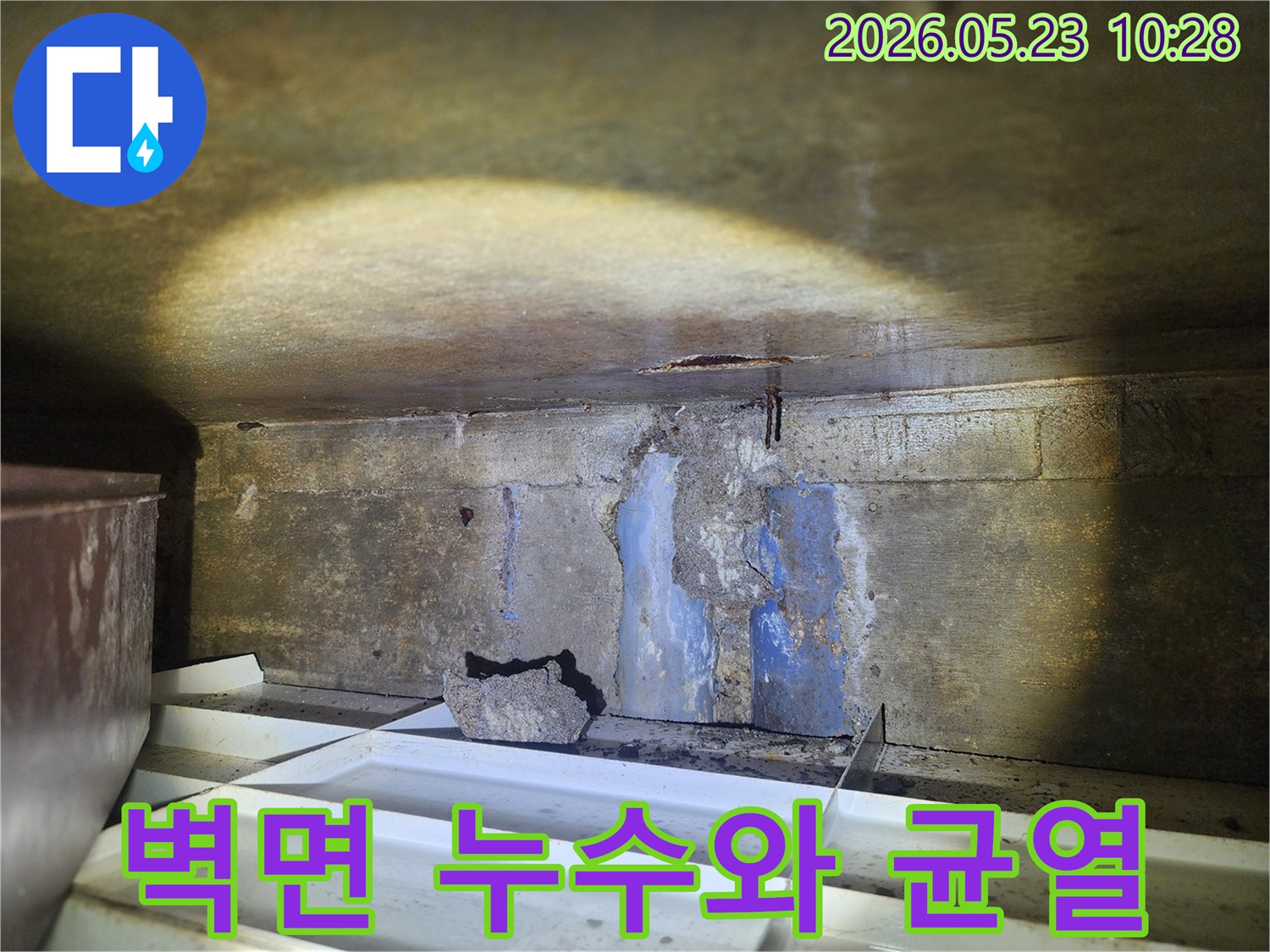 손상된-콘크리트-벽면에서-물이-새고-있으며-바닥에-물받이가-설치된-누수-현장