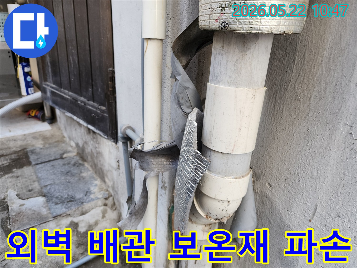 건물 외벽에 설치된 배관의 보온재가-보기 흉하게 찢어지고-벗겨진 모습입니다.