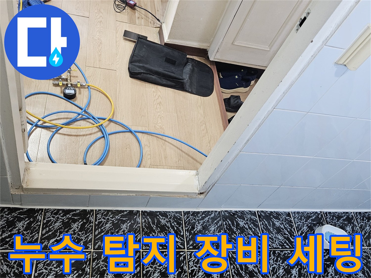 현관 앞 바닥에 배치된-가스 탐지기와 배관 점검용 호스