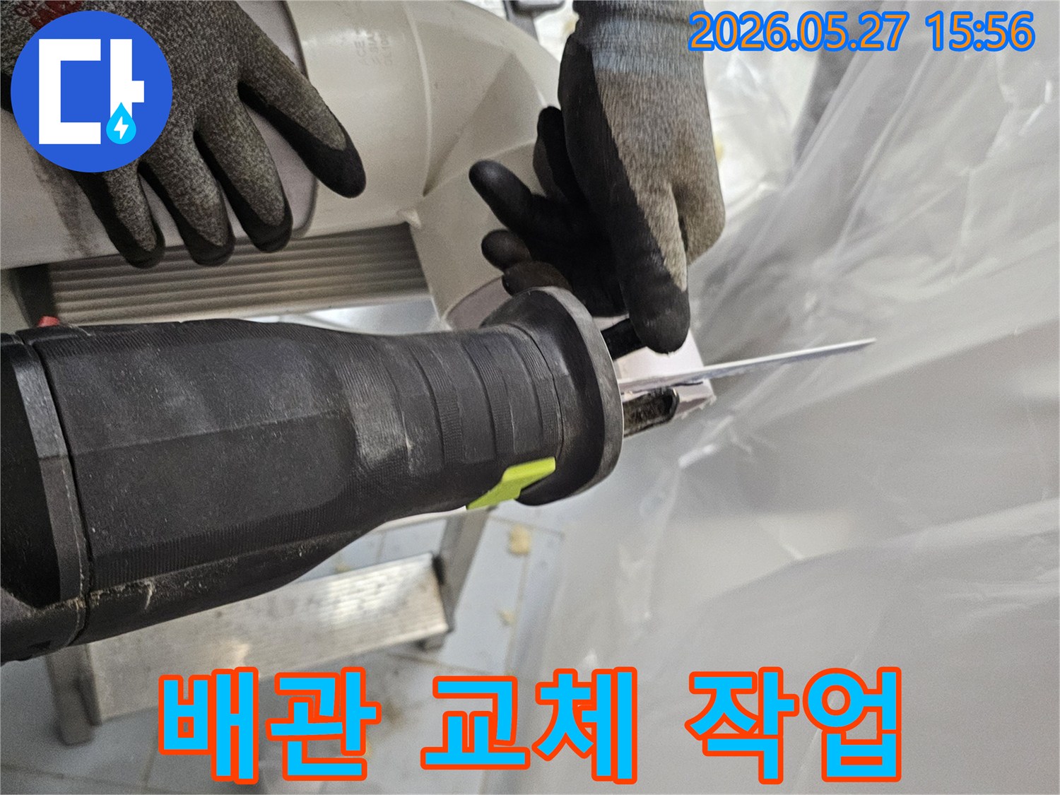 작업자가-안전장갑을-끼고-전동톱으로-오래된-PVC-파이프를-잘라내고-있습니다