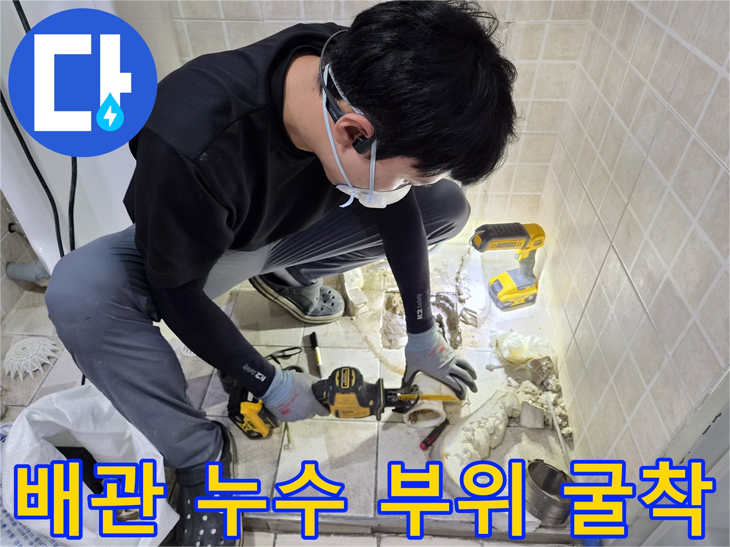 소변기 하단 배관의 결함을 찾기 위해 타일을 제거하고 작업하는 모습