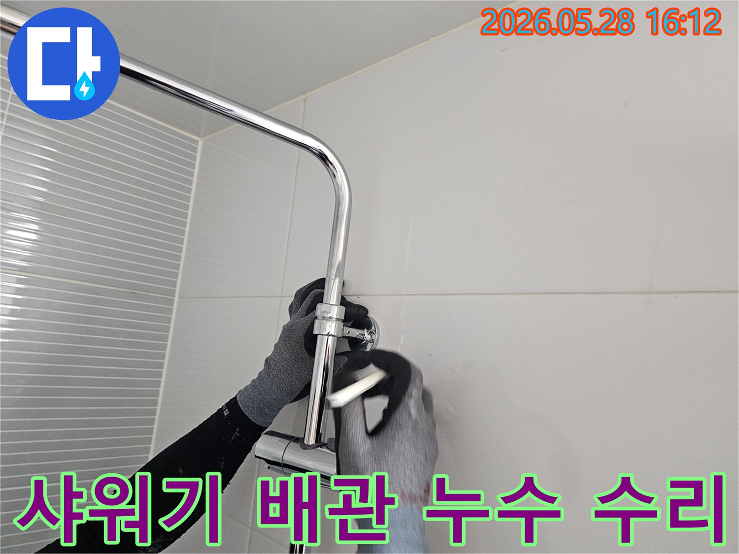 작업자가 장갑을 끼고-화장실 샤워기 배관을 점검하고 수리하는 모습입니다.