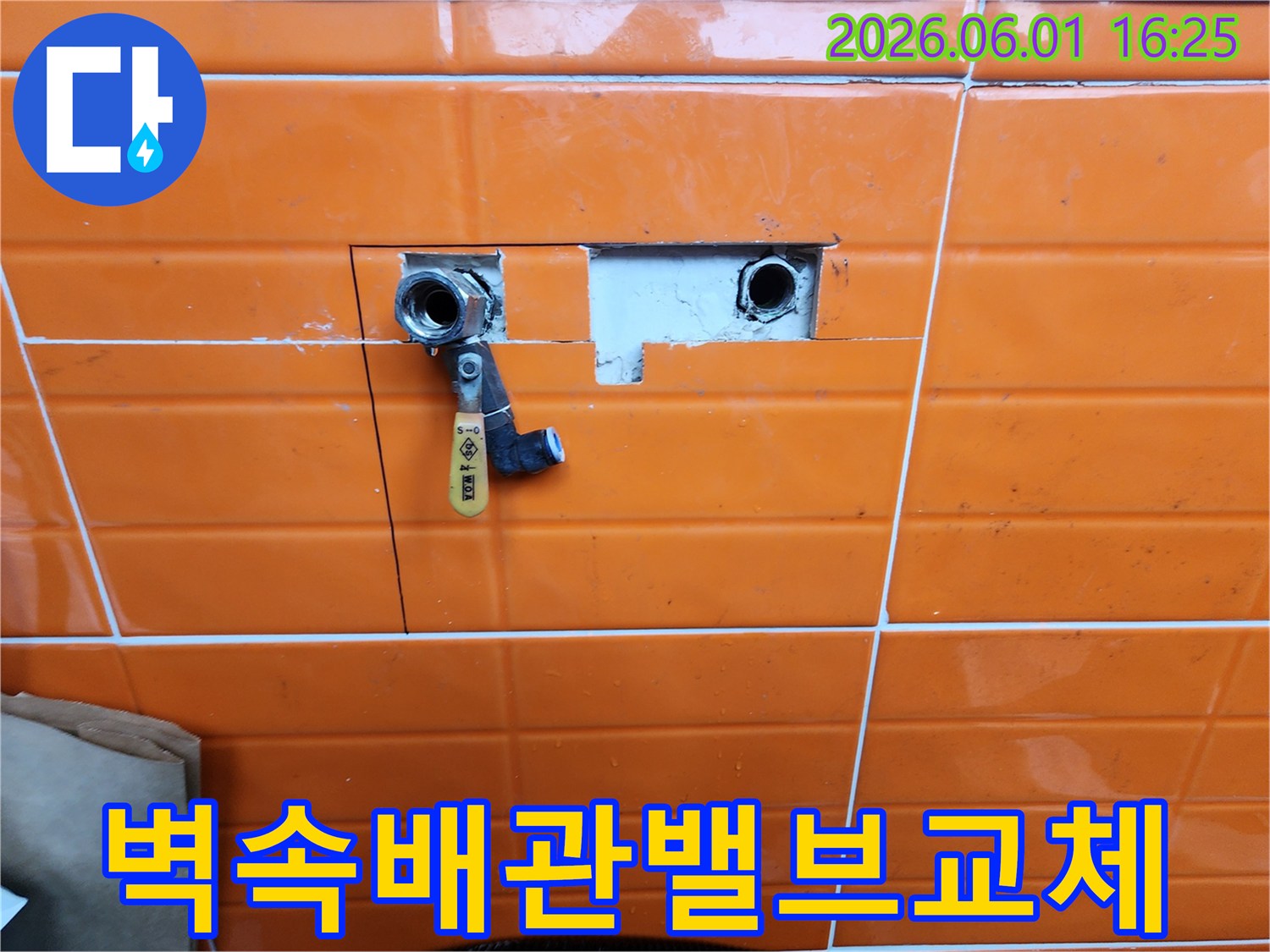 오렌지색-타일이-부분적으로-제거된-곳에-새로운-수도-밸브가-설치된-배관-수리-과정을-담은-사진입니다.