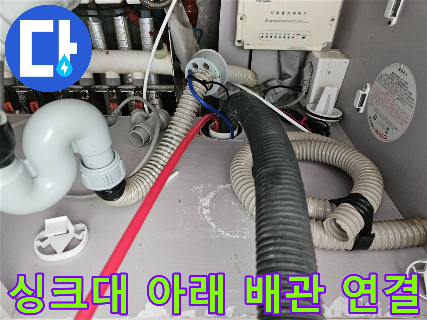 싱크대 하부의 복잡한 배수 및 급수 호스 연결 부위 상세 사진입니다.