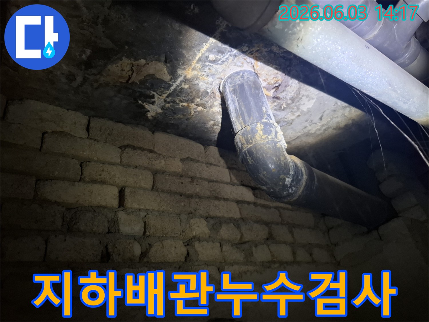 어두운 지하 공간에서-낡은 배관과-벽돌 벽에 발생한-누수 흔적을-조명으로 비춰-정밀하게 검사하는 모습