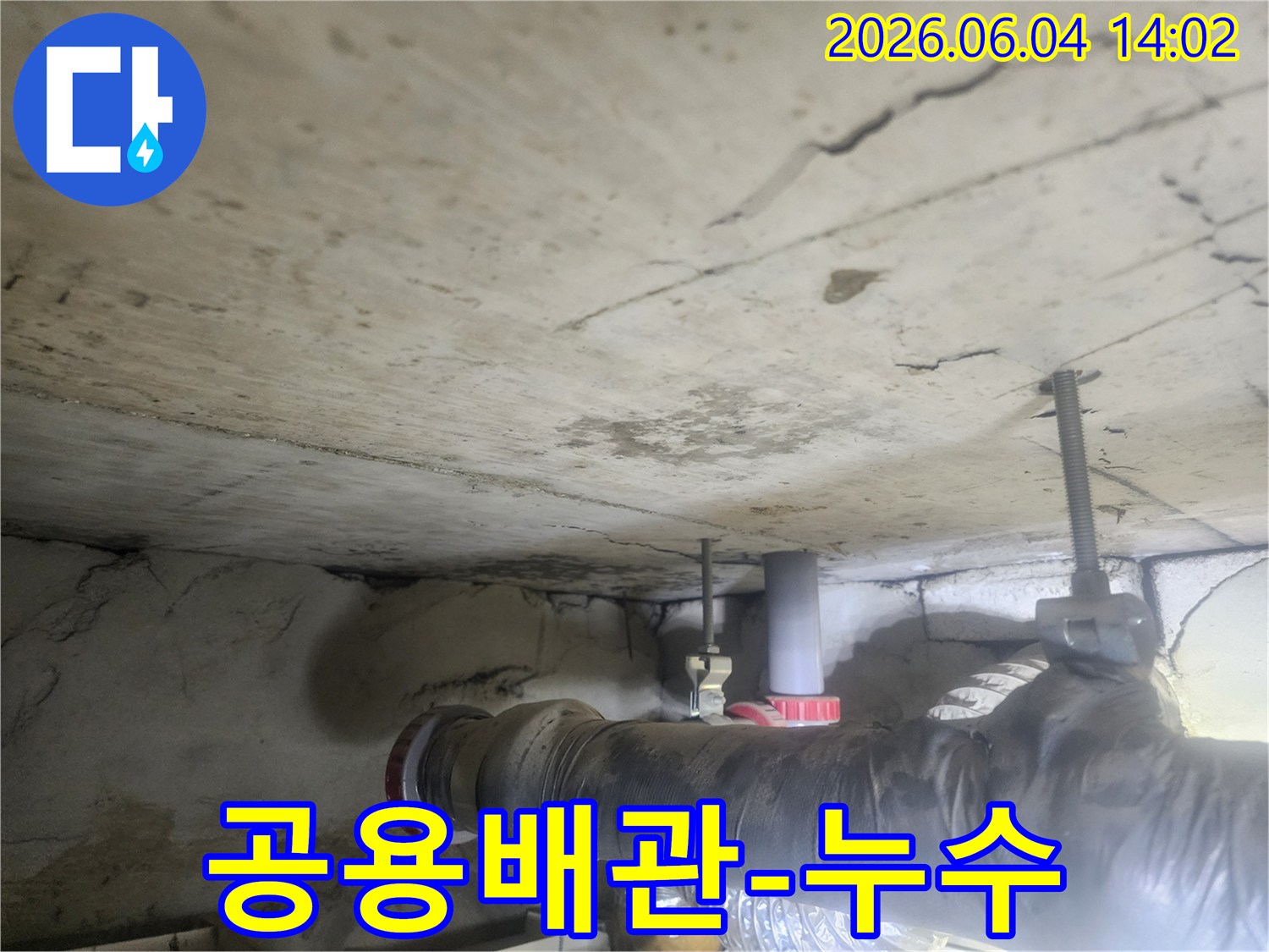 천장의 공용 배관 주변에-발생한 물 자국과-콘크리트 손상은-전문가의 개입이-필요함을 나타냅니다.