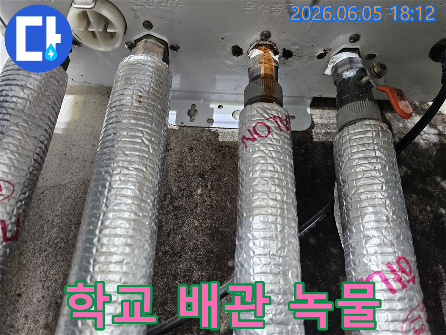 학교 보일러의 온수 배관에서-심각한 녹물과 부식으로 인해-누수가 진행되고 있음을-보여주는-현장 사진입니다.