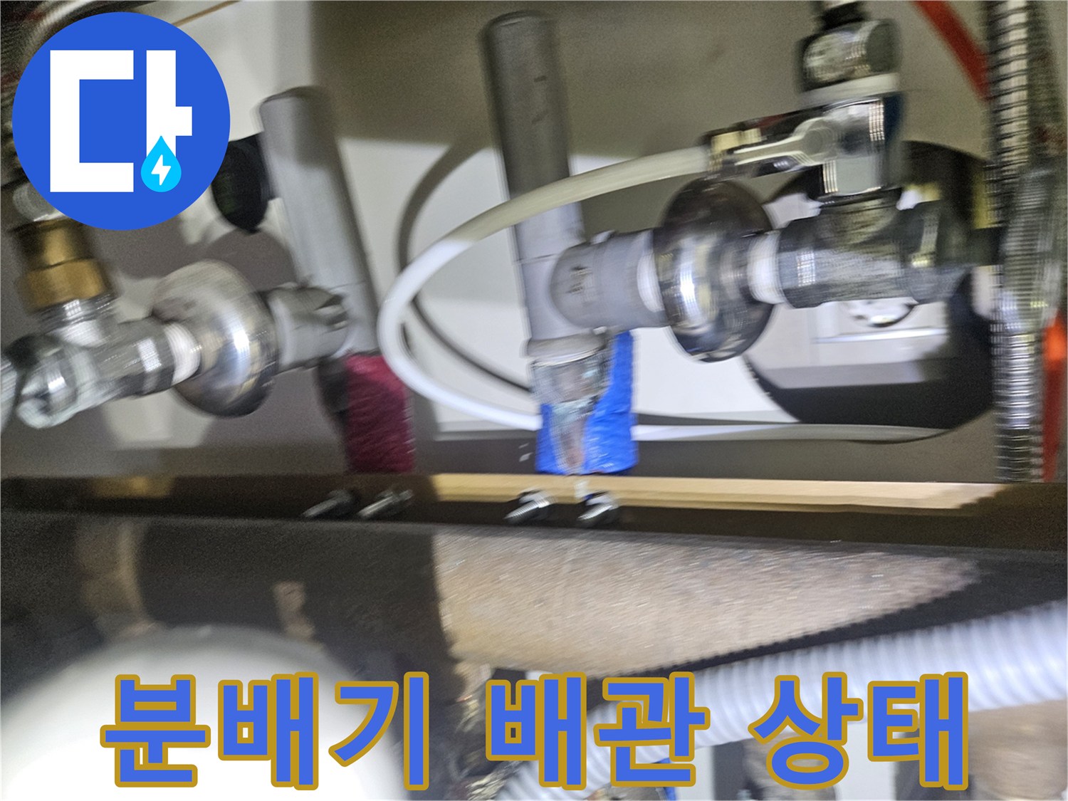 싱크대 하단 난방 분배기와 금속 커넥터 연결 부위의 정밀 검사 장면