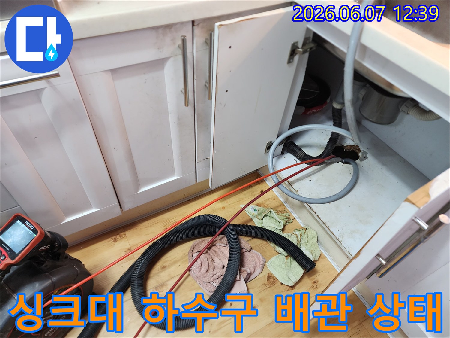 싱크대 아래쪽 배관과 내시경 장비가 배치된 작업 현장 사진입니다.