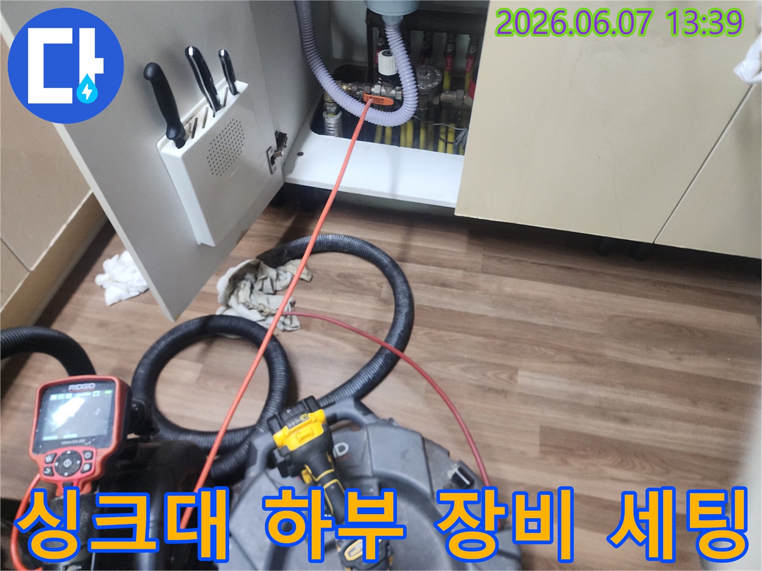 막힌 배관을 뚫기 위해 전문 장비를 싱크대 아래에 배치했습니다.