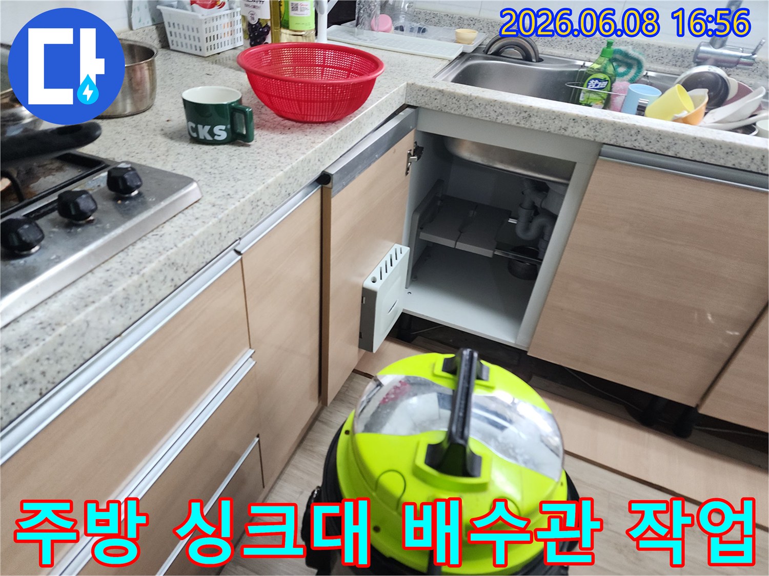 싱크대 하부장 내부 배관과 작업 중인 석션 기계의 모습