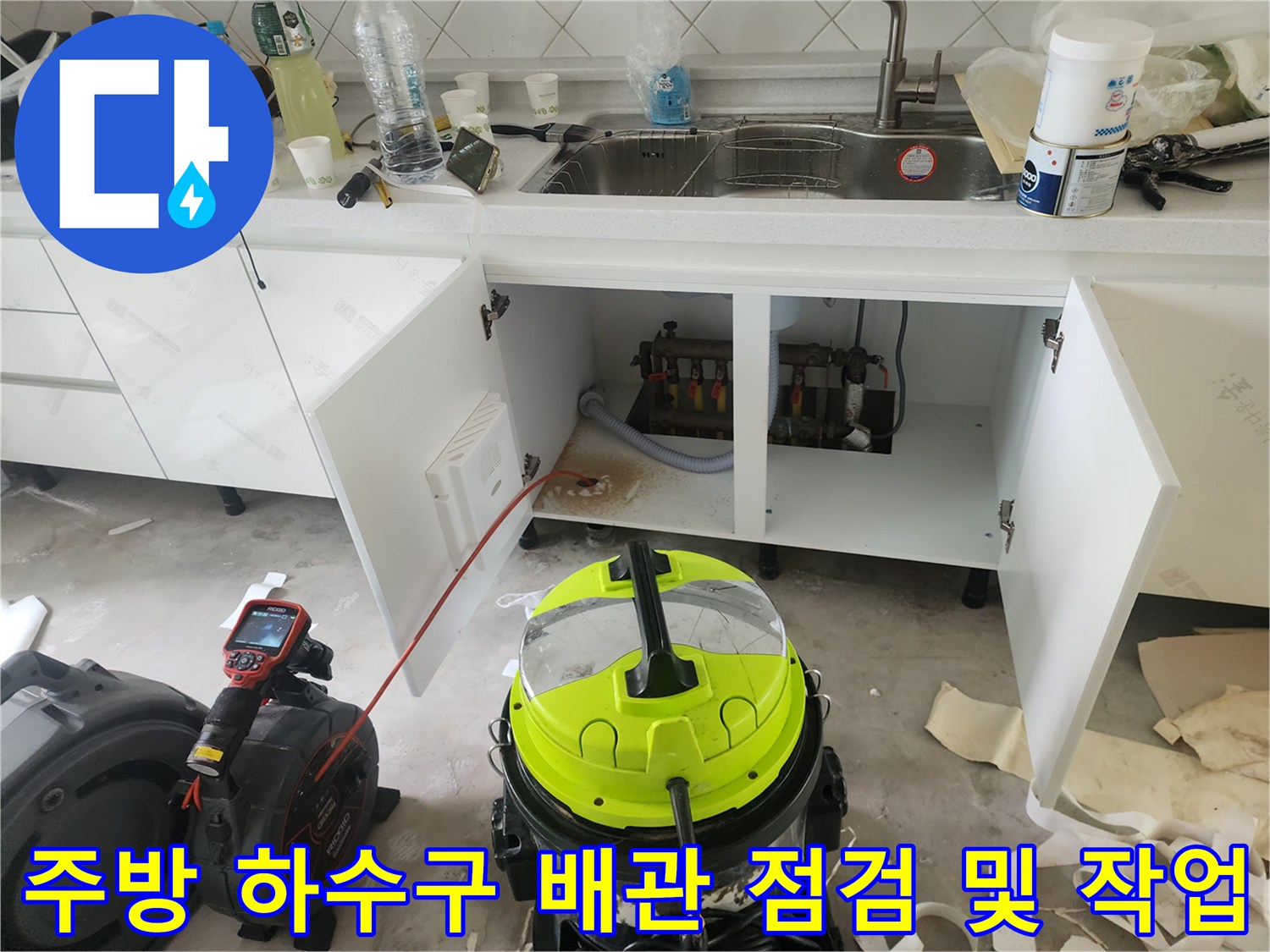 작업 중인 주방 싱크대 하부장 내부와 배관 장비들