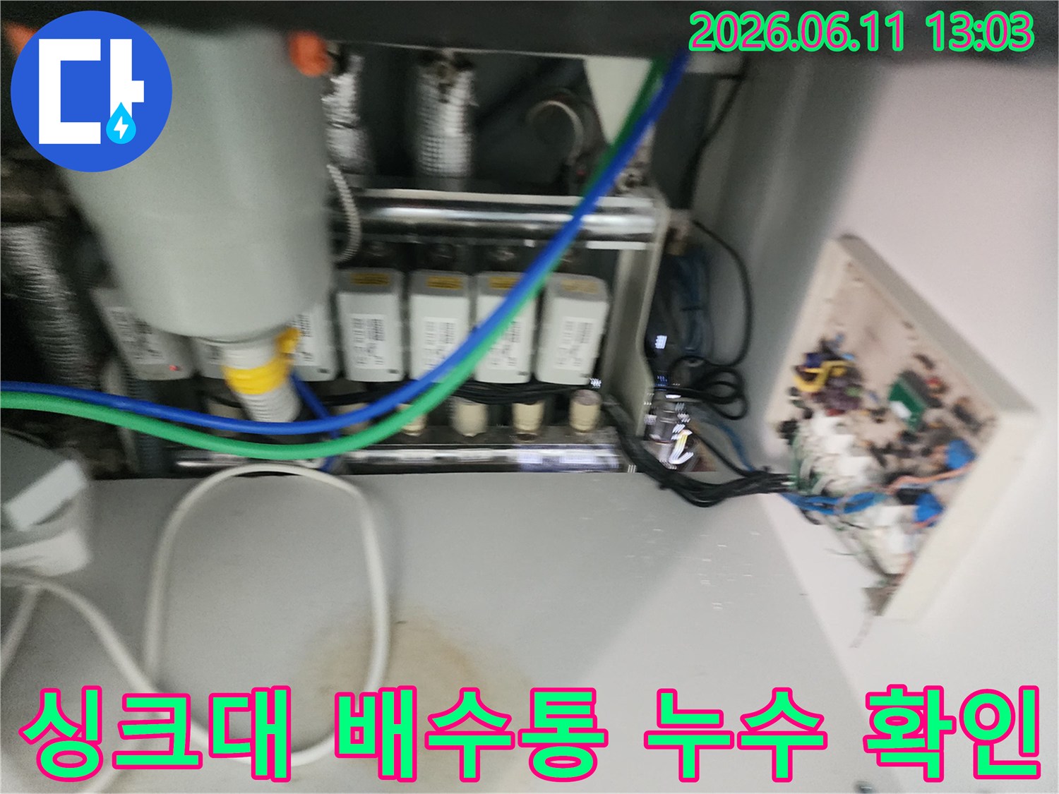 물이 새어 나오고 있는 싱크대 하부의 배수 연결 부위 모습입니다.