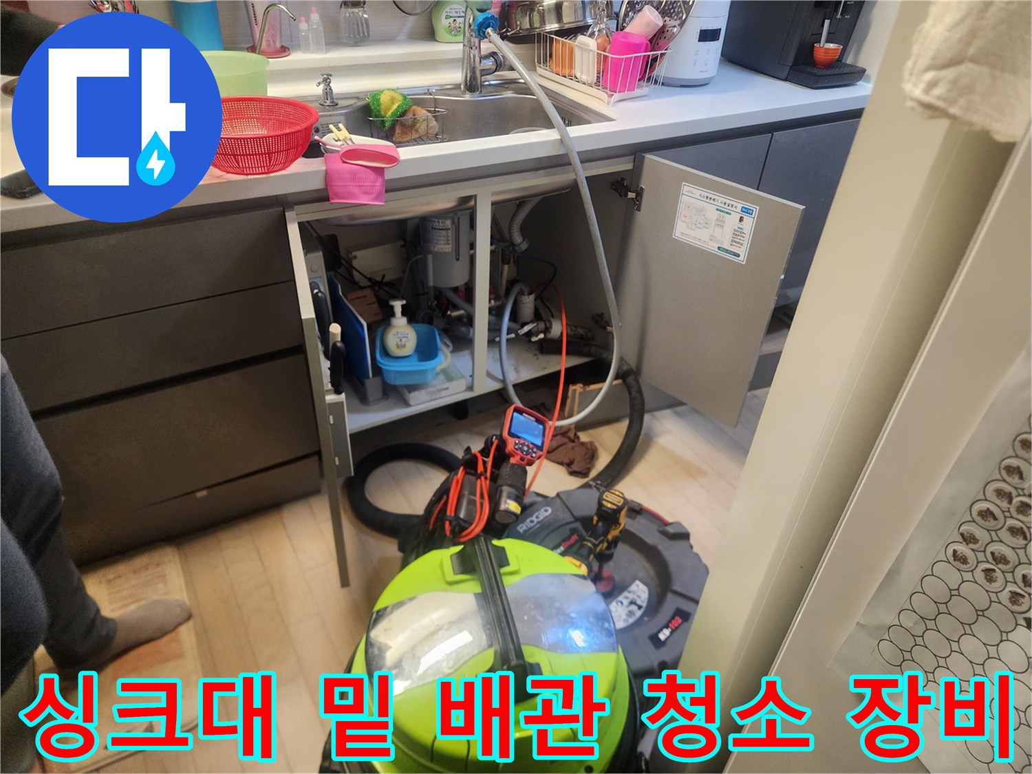 싱크대 하부장 공간에 배치된 전문적인 배관 세척용 장비입니다.
