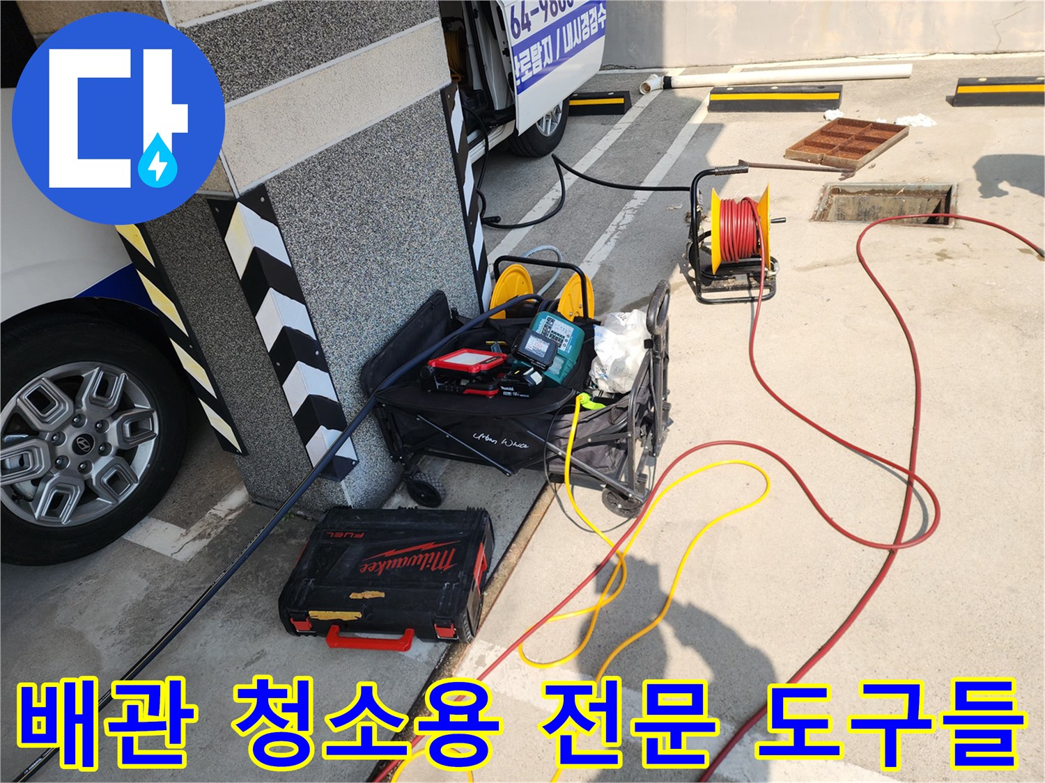 건물 외곽 작업 구역에 배치된 노란 호스 릴과 배관 내시경 장비함