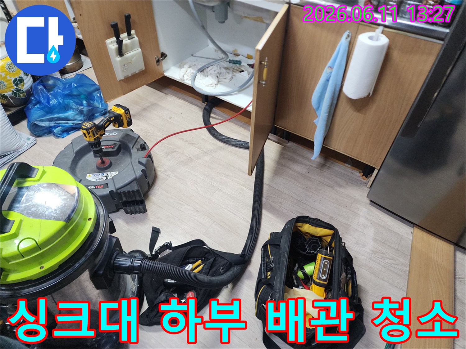 싱크대 밑 하부장 내부의 오염된 배수관을 확인하고 장비를 세팅한 장면