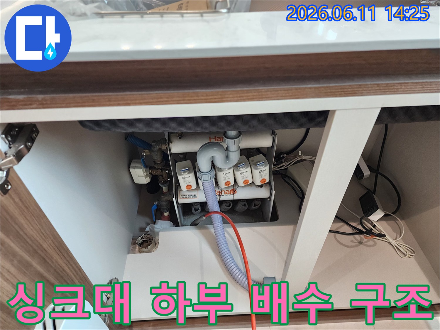 흰색 배수관과 파란색 호스가 연결된 싱크대 하부 배관의 모습입니다.