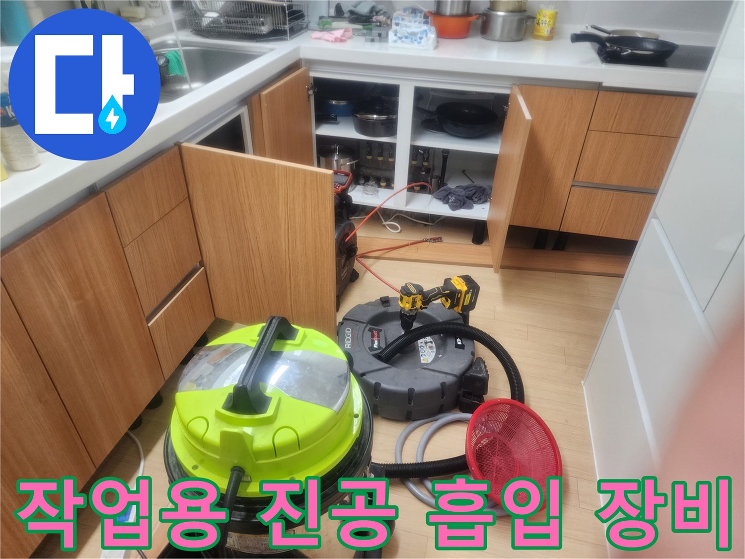 주방 싱크대 아래 작업 중인 배관 청소용 흡입기와 빨간 거름망