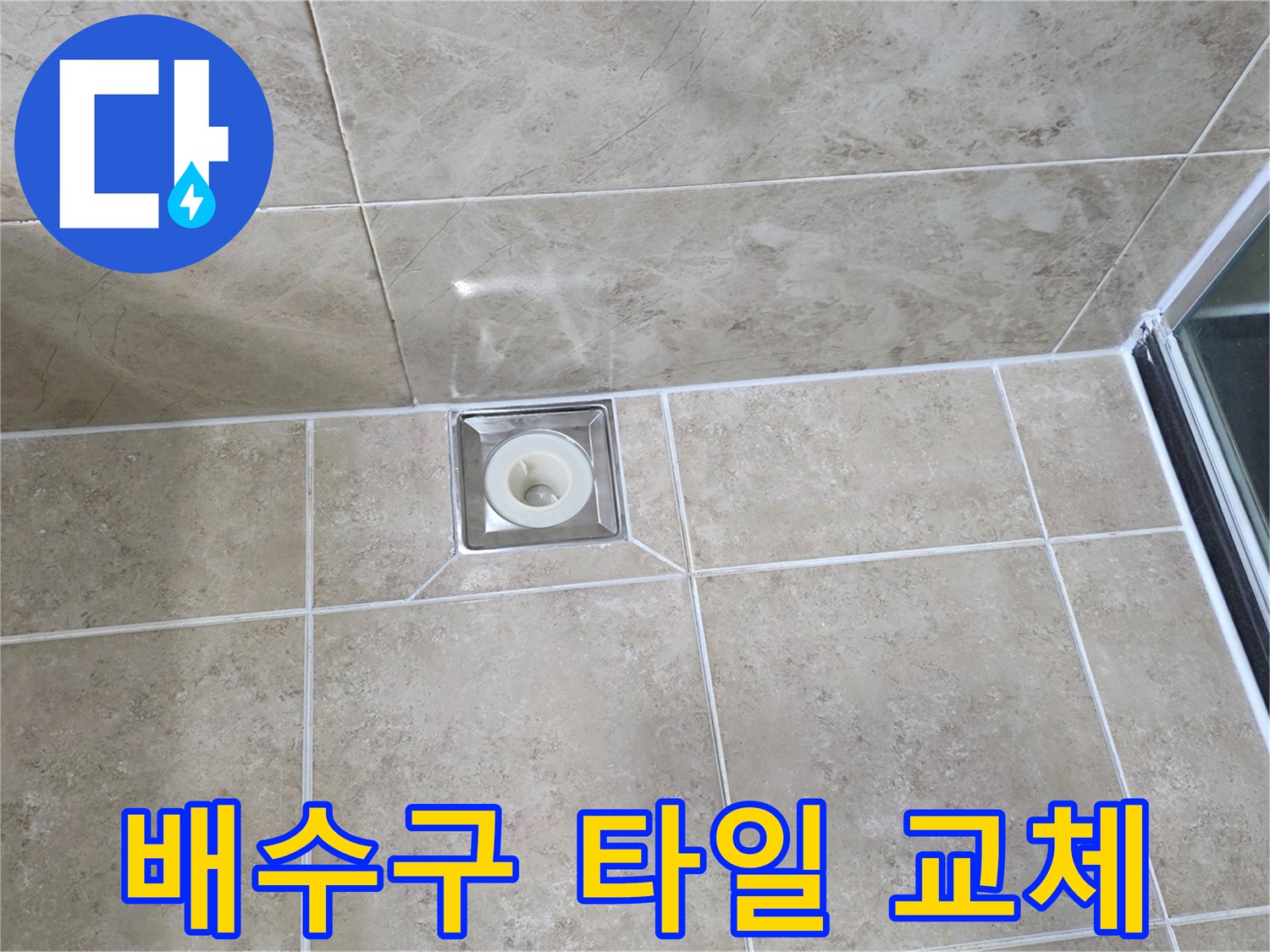 베이지색 타일 바닥에 위치한-사각형 금속 배수구의 모습으로-주변 타일의 접합부와-줄눈의 상태를 상세히 보여줍니다